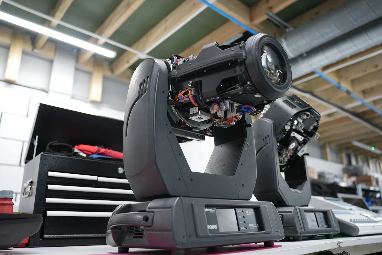 Two moving head lights with housings opened, exposing internal wiring and lens assemblies for repair.