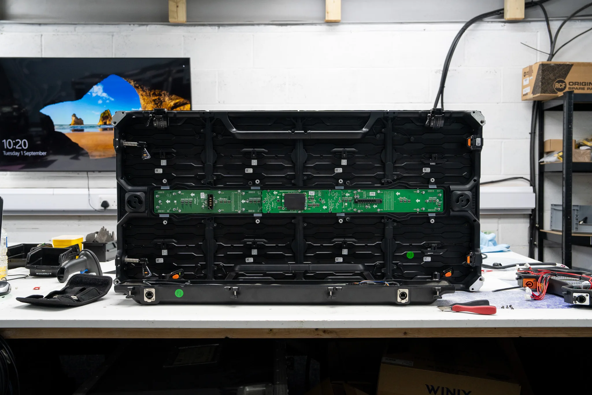 Rear panel of an LED display panel with the cover open, exposing green circuit boards and internal wiring.