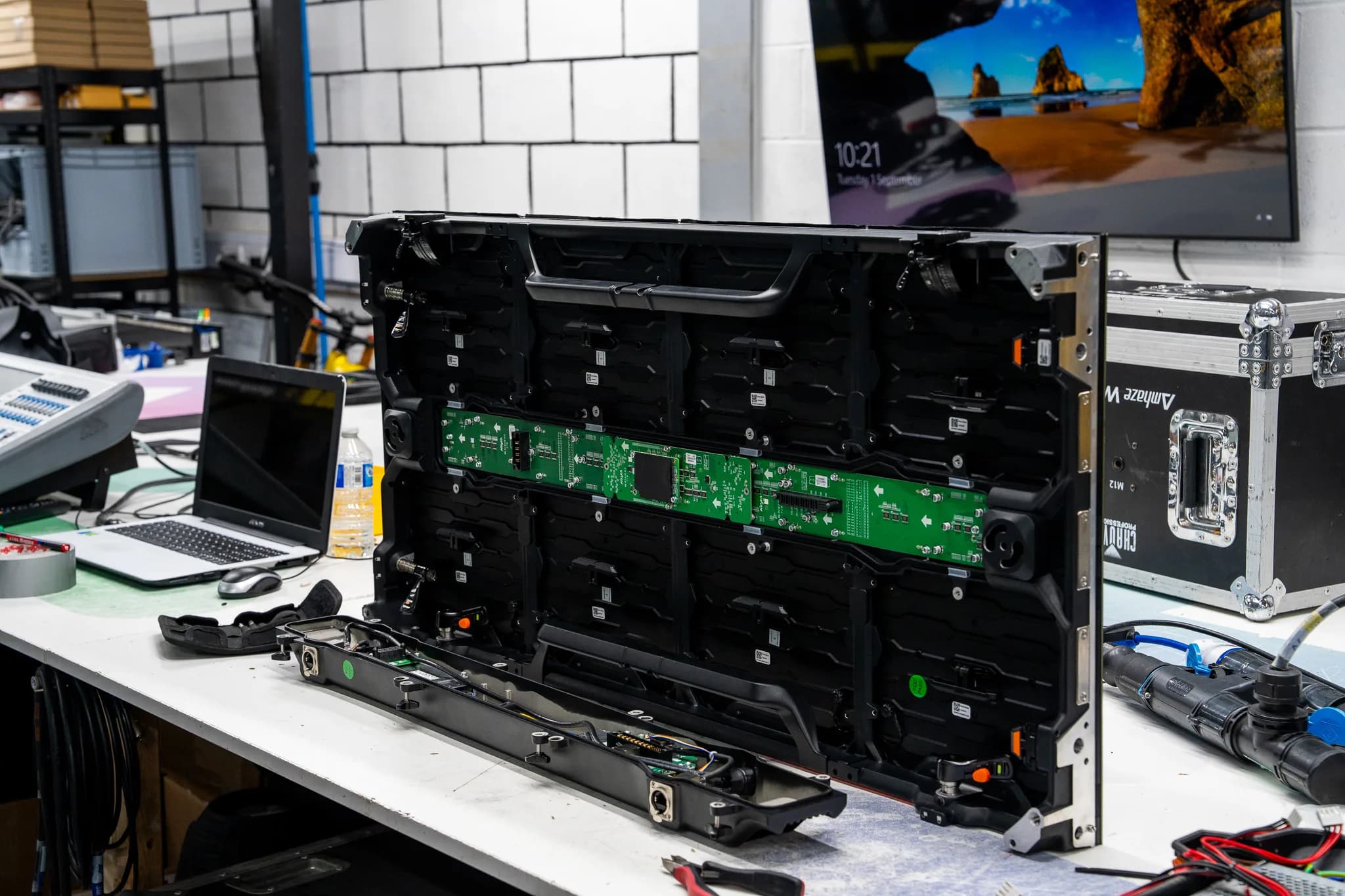 Rear of an LED display panel opened on a workbench, exposing its receiving card and internal frame.