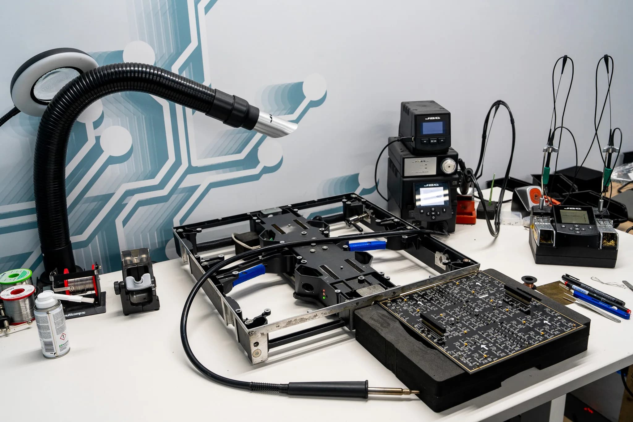 Repair bench with JBC soldering stations, a panel frame and driver boards seated in foam