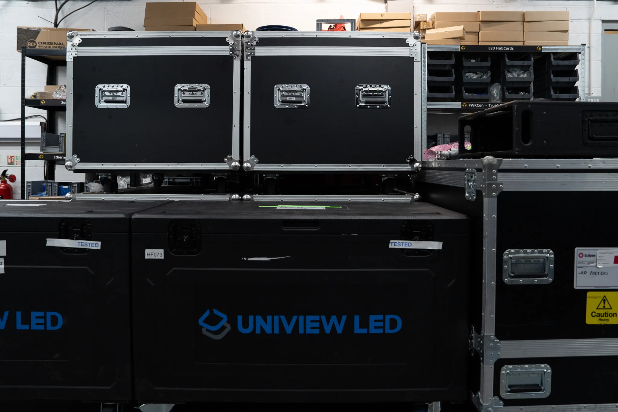 Flight cases stacked on Uniview LED crates marked as tested in the warehouse