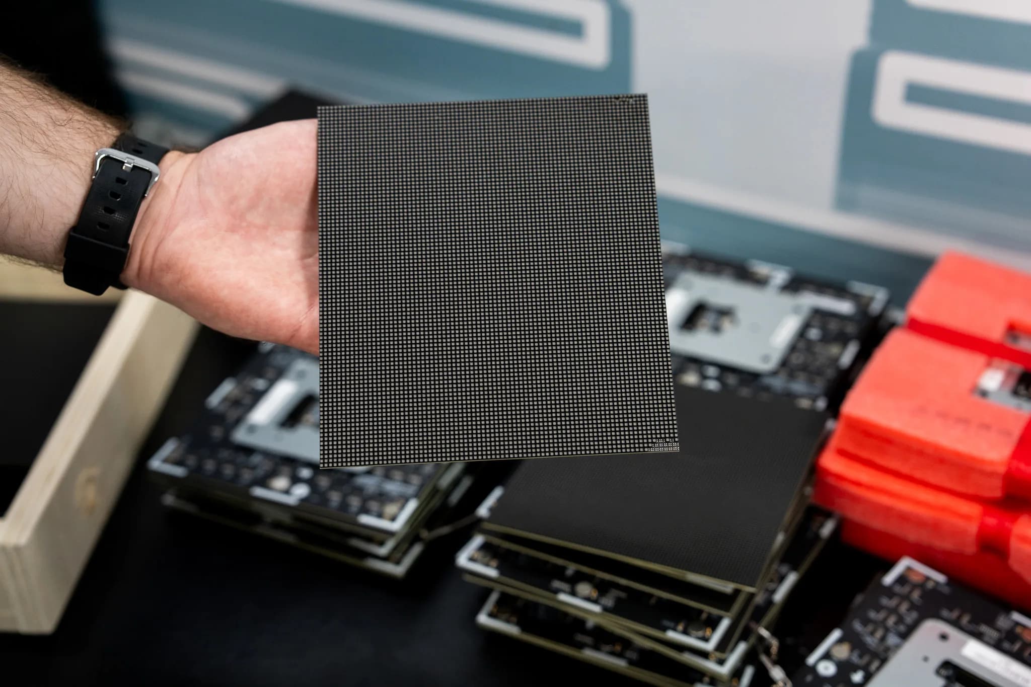 Hand holding an LED module above a stack of modules awaiting repair