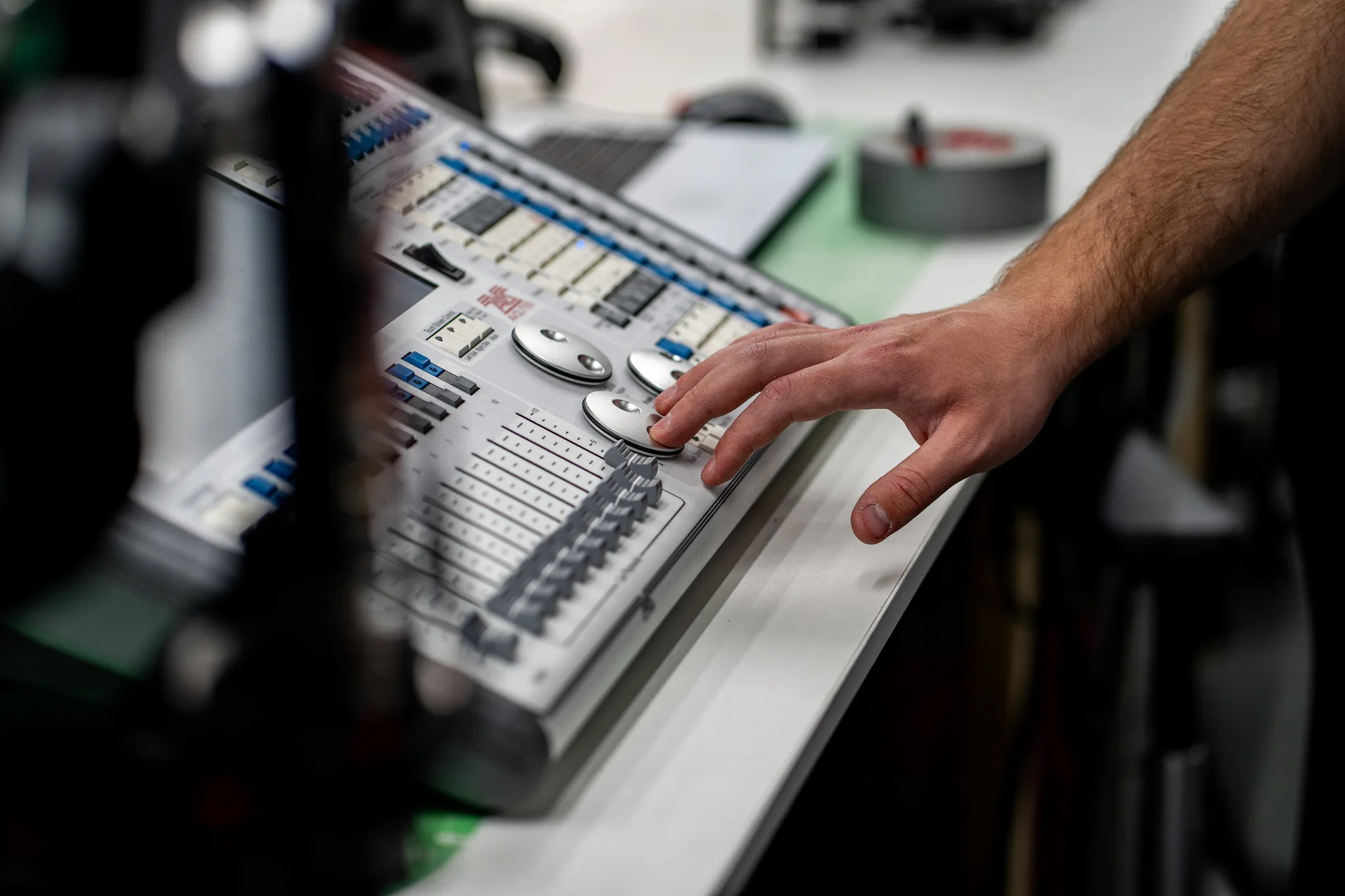 Hand on the encoder wheels of a lighting control console during testing at the bench