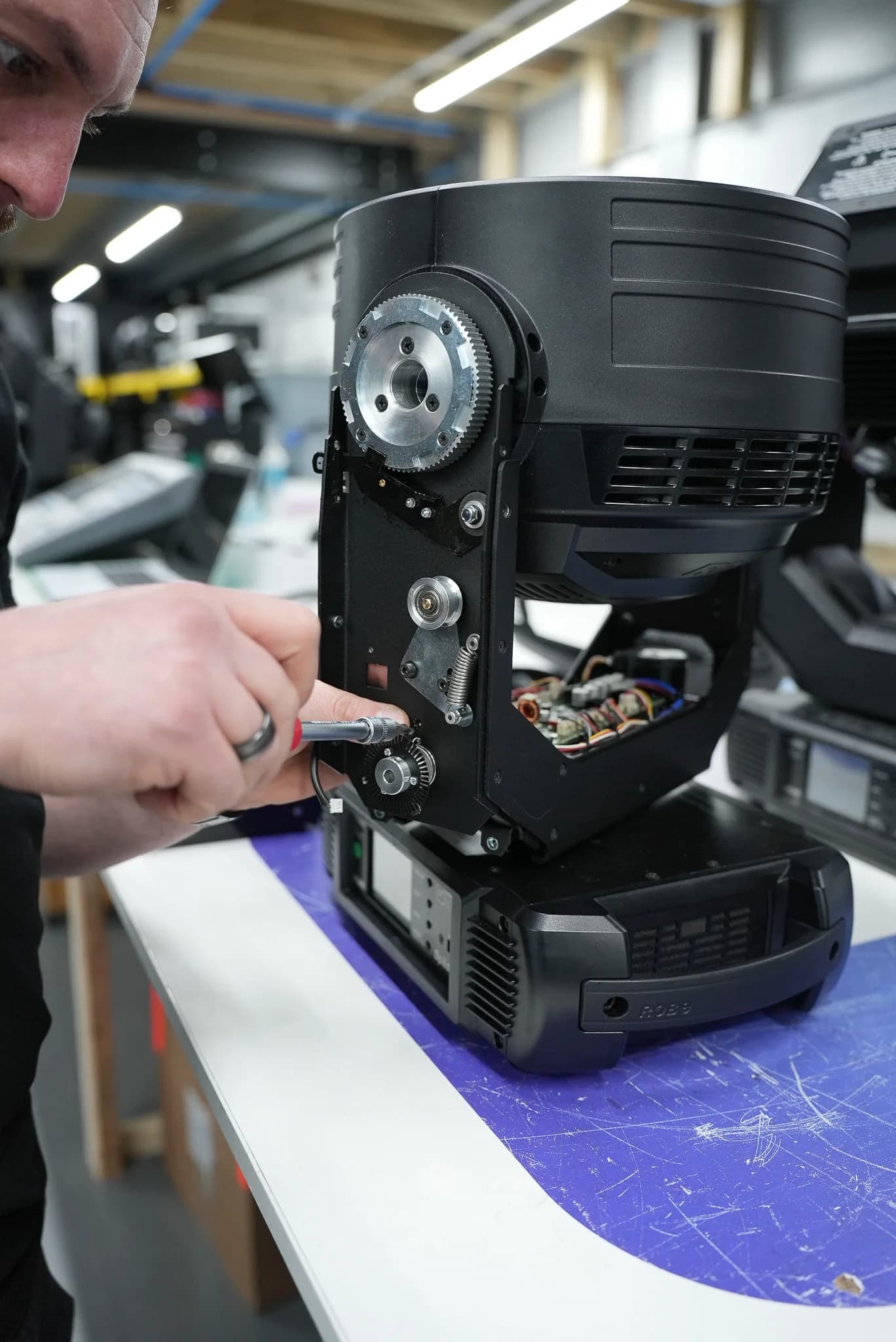 Close up of a CPS technician adjusting the pan and tilt gear drive inside an opened Robe moving head on the repair bench