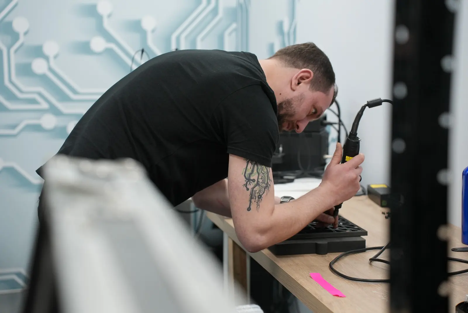 Technician using a screwdriver to repair a component on a workbench in a repair shop.